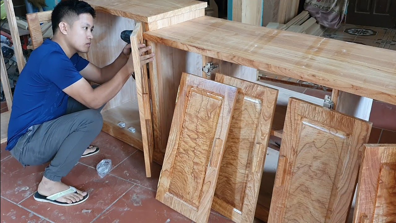 A worker is working with wooden cabinets